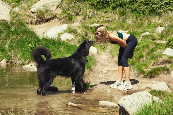Mulher Loira Beijando Grande Cão Preto Livre — Fotografia de Stock