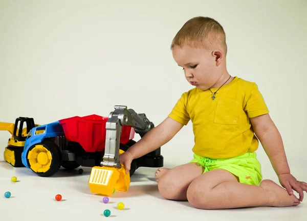 little boy playing with a toy truck with a manipulator on a white background
