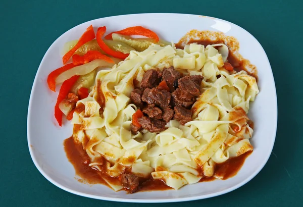 Rundvlees vlees goulash met pasta en fruit salade — Stockfoto