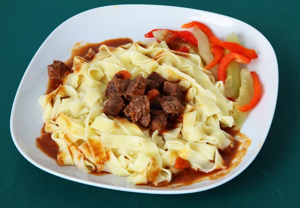 Beef meat goulash with pasta ,pepper and sour cucumbers — Zdjęcie stockowe