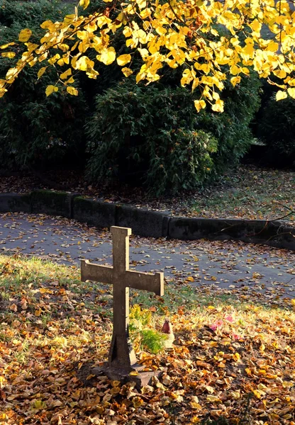 Крест на могиле на кладбище осенью — стоковое фото