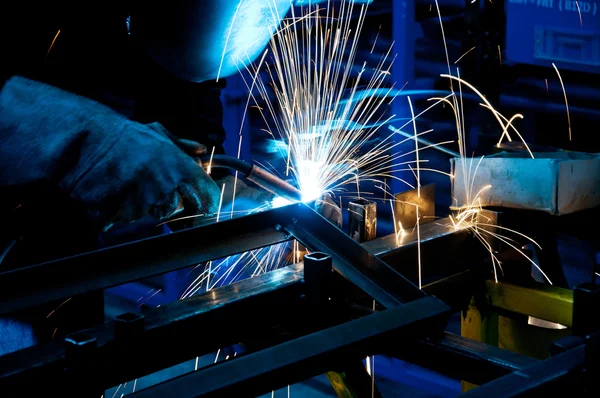 Menschliches Schweißen mit vielen Funken in einer Metallindustrie — Stockfoto