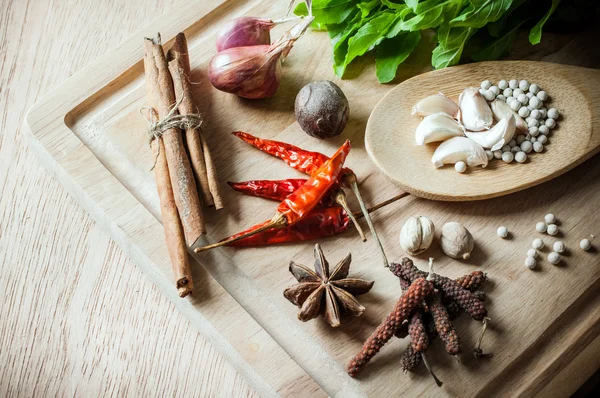 Herbs and spices on wood chopping block — Stock Photo, Image