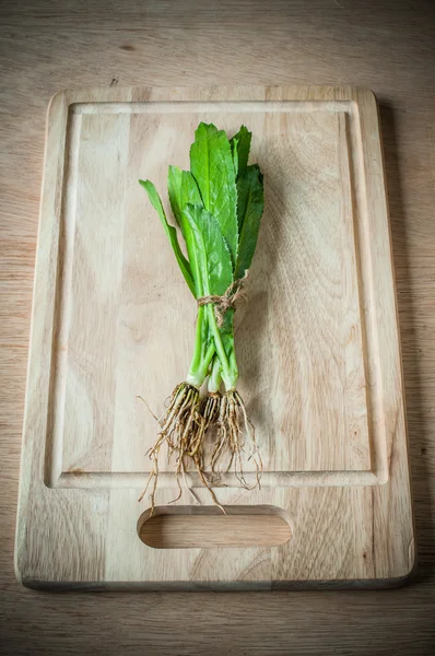 Long coriander leaves on chopping block — Stock Photo, Image