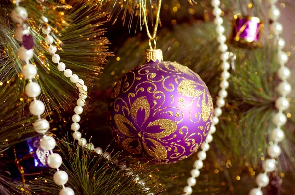 Hermosas decoraciones de Navidad púrpura colgando en el árbol de Navidad con resplandor brillante —  Fotos de Stock