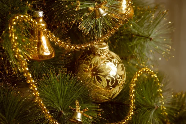 Красивые золотые рождественские украшения, висящие на рождественской елке с блестящими бликами — стоковое фото