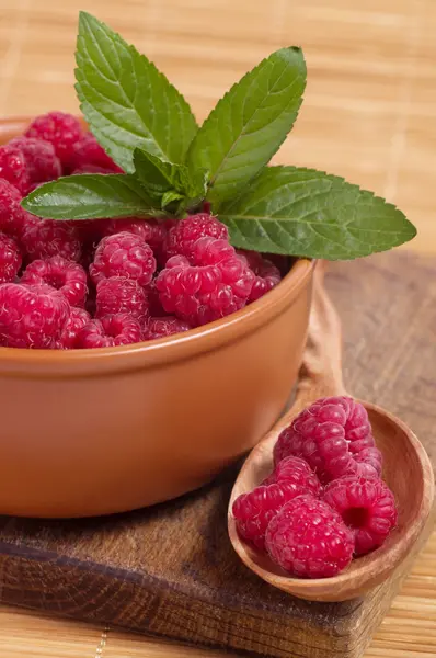 Wooden spoon and bowl with raspberries — Stock Photo, Image