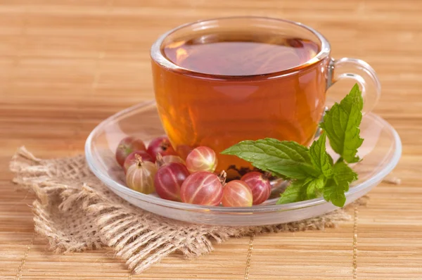 Fruit tea(tea package) in cup with gooseberry — Stock Photo, Image