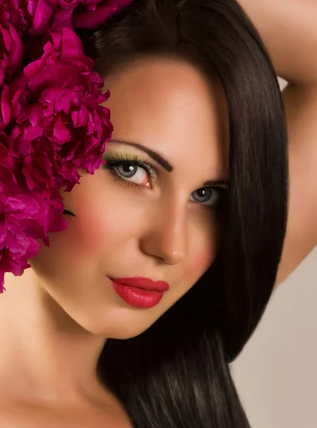 Piękna twarz młodej kobiety z czerwonych kwiatów — Zdjęcie stockowe
