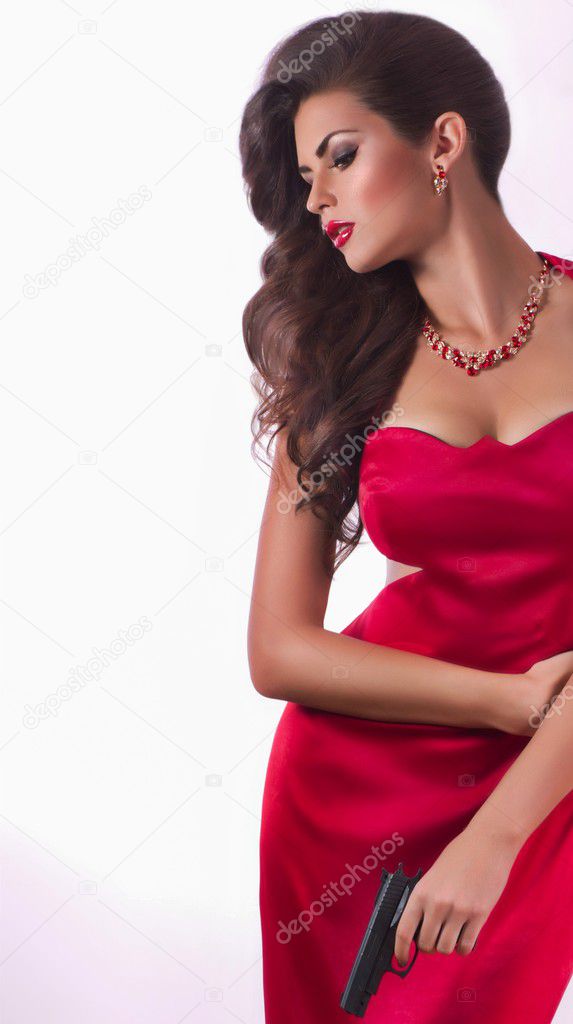 Beautiful young woman with revolver in red dress
