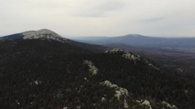 Taganay Ulusal Parkı 'nın havadan görünüşü. Otkliknoy sırtındaki inanılmaz gri kayalar. Kruglitsa Dağı manzarası. Güney Ural. Bulutlu hava, sonbahar, yürüyüş, turizm. İHA video çekimi