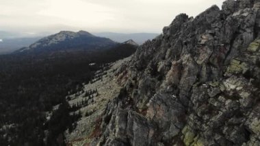 Taganay Ulusal Parkı 'nın havadan görünüşü. Otkliknoy sırtındaki inanılmaz gri kayalar. Kruglitsa Dağı manzarası. Güney Ural. Bulutlu hava, sonbahar, yürüyüş, turizm. İHA video çekimi