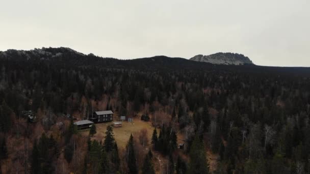 Uitzicht vanuit de lucht op het naaldbos in de herfst bij de top van de berg. Er zijn kleine houten huisjes en zonnepanelen. Kleine paden gaan het bos in. Wandelen, het leven weg van de stad — Stockvideo
