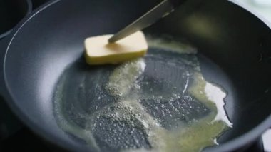 Altın tereyağı, elektrikli sobanın üzerinde yavaş yavaş erimeye başlar. Yağ sıvıya dönüşür ve ısınır. Parça sıcak yüzey üzerinde spatula ile yavaşça hareket eder. Evde yemek pişirme, kilitleme.