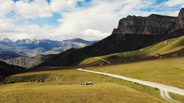 Αεροφωτογραφία του ορεινού περάσματος, Βόρειος Καύκασος. Το εύρος των κορυφών των βουνών φωτίζει τον λαμπερό ήλιο. Πλαγιές καλύπτονται με πλούσια βλάστηση και βράχους. Η σκιά των νεφών τρέχει στα λιβάδια — Αρχείο Βίντεο