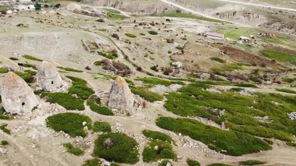 Vista aérea das criptas de pedra cinzenta da cidade dos mortos, Cáucaso. Casas brilhantes com telhados pontiagudos em declive entre vegetação baixa e pedras. Antigo enterro tradicional caucasiano — Vídeo de Stock