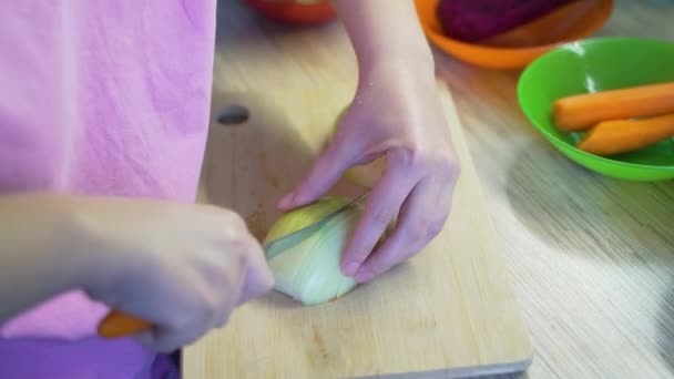 女人们在厨房里用锋利的小刀把新鲜的洋葱片放在木板上烹调。小块一块一块地落在木板上.健康饮食、蔬菜、家庭烹调 — 图库视频影像