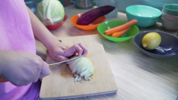女人们在厨房里用锋利的小刀把新鲜的洋葱片放在木板上烹调。小块一块一块地落在木板上.健康饮食、蔬菜、家庭烹调 — 图库视频影像