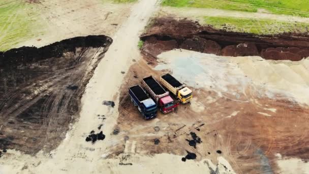 Flygfoto av stora lastbilar med färsk asfalt i släpvagnar för vägbyggen vid provningsplatsen för bilar. Byggnadsarbeten pågår. Vägbyggnad, provningsplats — Stockvideo