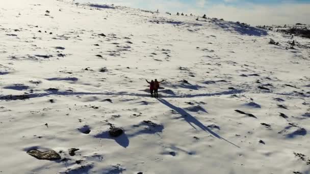 Ilmakuva lumiselle vuorenrinteelle, Etelä-Uraliin. Turistit seisovat polulla lumen peittämällä niityllä vuoren juurella. Sininen taivas on valkoisten pilvien peitossa. Aurinkoista. Vaellus — kuvapankkivideo