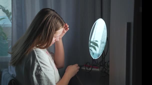 Молодая женщина смотрит на себя в зеркало, осматривает кожу лица и расстраивается. На лице покраснение и прыщи. Девушка расстроена. Здоровье, косметология — стоковое видео