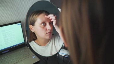 Genç bir kadın aynada kendine bakar, yüzünün derisini inceler ve üzülür. Yüzünde kızarıklık ve sivilceler var. Kız çok üzgün. Sağlık, kozmetoloji