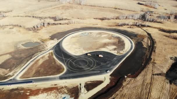 Vue aérienne de l'achèvement de la construction routière du terrain d'essai pour les voitures. Bitume noir avec des marques routières claires, blanches et jaunes, de différentes formes. Construction de routes, terrain d'essai — Video