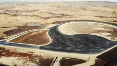 Arabaları test etmek için yeni yolun havadan görünüşü. Beyaz ve sarı işaretli taze siyah asfalt. Siyah asfalt üzerinde boşluk olan sağlam çizgiler ve çizgiler. Test alanı