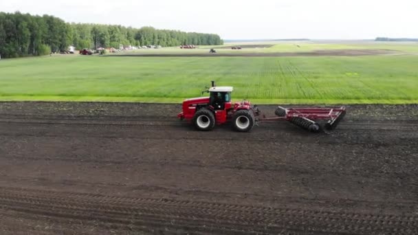 Red harvester drives across field and plows earth. Sows grain in field. He drives and leaves tracks in form of stripes. Russian field, harvesting, grain, agriculture, cultivation, modern technologies — Video