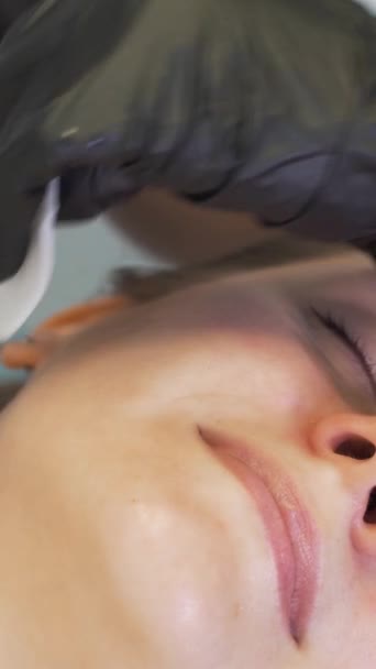 Kosmetolog čistí pokožku pomocí ultrazvukového čisticího zařízení. Lékaři v rukavicích přejíždějí po tváři klientů kovovou destičkou. Omlazovací procedura, léčba akné a pupínků — Stock video