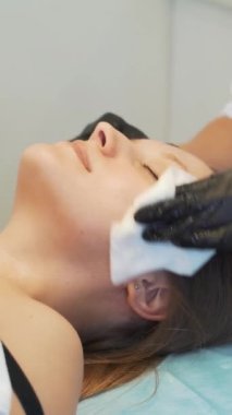 Kozmetik uzmanı genç kadınların yüzlerini çamurdan ıslak beyaz süngerlerle siliyor. Hastaları safsızlıklarından arındırmak için cildini nazikçe ovuyor. Modern kozmetoloji, akne tedavisi, sivilce, gençleştirme