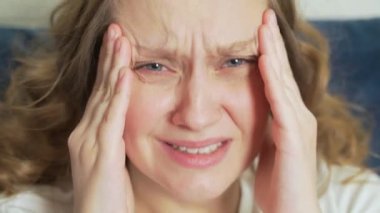 Genç bir kadın baş ağrısı, migren ve spazmlar nedeniyle şakaklarına masaj yapıyor. Yüzünde ıstırap, acı, umutsuzluk var, derin derin nefes alıyor. Soğuk algınlığı, grip, migren, salgın, kramp