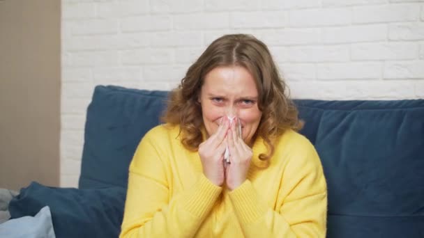 Vrouw niest en snuit haar neus in zakdoek, ze heeft verkoudheid, griep, pandemie, infectie. Ze is allergisch. Ze wrijft in haar neus, knijpt in de zakdoek en legt hem op tafel. Rhinitis — Stockvideo