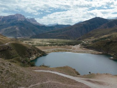 Gök mavisi Gizhgit Gölü, Kafkasya 'nın havadan görünüşü. Mavi su gün ışığında parıldıyor. Yüksek görkemli dağ sırası görülebilir. Bulutlu gökyüzünde sivri tepeler parlıyor. İHA ateşi