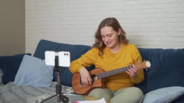Kadın öğrencilere ukulele çalmayı öğretiyor. İnsanlara doğrudan video bağlantısıyla anlatıyor. Enstrümanın tellerini nasıl yeneceğini anlatıyor. Bloglama, çevrimiçi eğitim