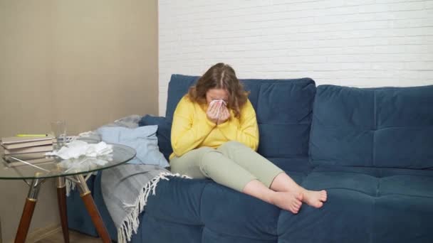 Vrouw niest en snuit haar neus in zakdoek, ze heeft verkoudheid, griep, pandemie, infectie. Ze is allergisch. Ze wrijft in haar neus, knijpt in de zakdoek en legt hem op tafel. Rhinitis — Stockvideo