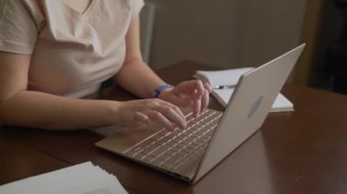 Kadın eller dizüstü bilgisayarın klavyesinde yazı yazıyorlar. Parmaklar klavyedeki tuşlara hızlıca basın. Onun yanında bir defter var. Kişisel bilgisayar, evde uzaktan çalışma, iş, çalışma, mesajlaşma, sohbet