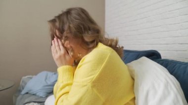 Kazaklı kadın yatağa oturur, öksürür ve hapşırır. Üşütmüş, grip olmuş, koronavirüsü var. Boğazı ağrıyor. Ateşi var ve kendini battaniyeye sarmış. Grip, soğuk algınlığı, koronavirüs salgını izolasyonu.