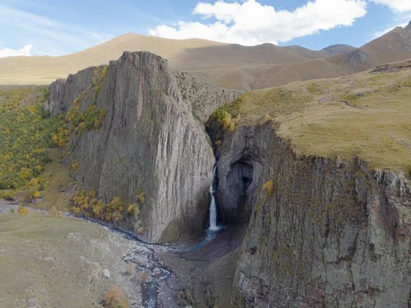 Luftfoto af det store vandfald, Kaukasus. Kraftfuld strøm af rent vand løber fra den smeltende gletsjer, falder ned fra bjergene og den blå flod flyder. Hårde sten over det hele. Vild natur Royaltyfrie stock-fotos