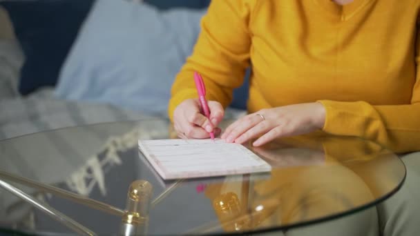 Γυναίκα γράφει κάτι σε φύλλα χαρτιού σε γυάλινο τραπέζι με στυλό. Διαβάζει κάτι και το διορθώνει με στυλό. Μελετώντας κάτι, προετοιμάζοντας για την ομιλία, ελέγχοντας το συμβόλαιο, την κατάρτιση, διάλεξη — Αρχείο Βίντεο