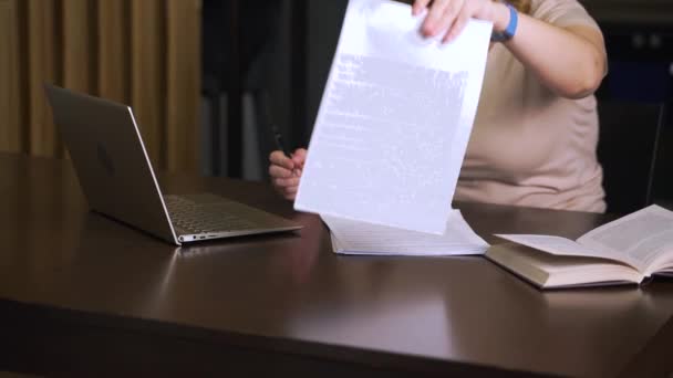 Μια γυναίκα υπογράφει χαρτιά για δουλειά ή μελέτη. Έχει ένα σωρό συμβόλαια μπροστά της, βάζει την υπογραφή της στο σεντόνι και τα αφήνει στην άκρη. Εργασία στο σπίτι, e-learning, πανδημία, καραντίνα, απόσταση — Αρχείο Βίντεο
