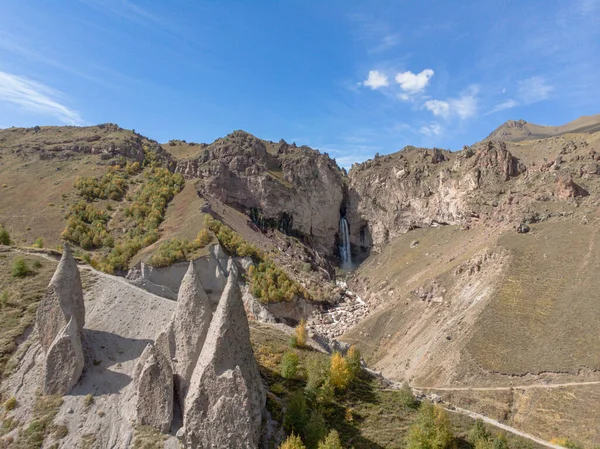 Dağ şelalesinin havadan görünüşü, Elbrus. Dağdaki keskin tepeler görülebilir. Fırtınalı nehir dağın tepesinden vadiye doğru akıyor ve yerden kırılıyor. Güneşli hava