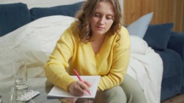 Kadın cam masadaki kağıt üzerine kalemle bir şeyler yazıyor. O bir şey okur ve onu kalemle düzeltir. Bir şeyler çalışmak, konuşmaya hazırlanmak, kontratı kontrol etmek, eğitim, konferans.