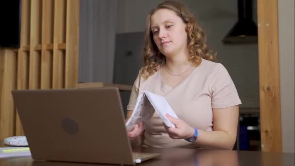 Женщина Сидит Столом Открытым Ноутбуком Блокнотом Перед Ней Надевает Очки — стоковое видео