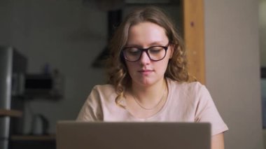 Gözlüklü kadın dizüstü bilgisayarda biriyle mesajlaşıyor ya da iş raporu hazırlıyor. Sakin ve bir şeyler yazıyor. E-öğrenme, evde çalışma, karantina, mesafe
