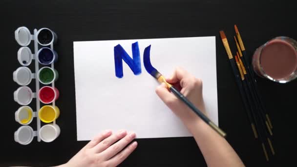 Homme peint affiche pour le rassemblement avec le slogan NON À LA GUERRE. Avec des pinceaux et des peintures, il imprime des lettres vives colorées sur une feuille. Exigence de personnes. Affiche avec appel, rassemblement, piquet, marche, protestation, action — Video