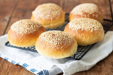 Tahta arka planda susam tohumlu taze pişmiş hamburger çörekleri. Kapat.. 