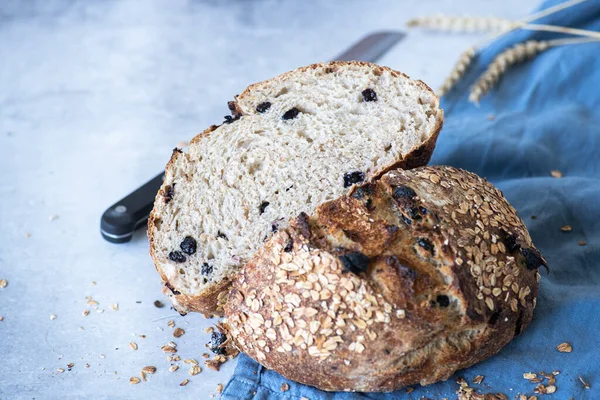 Sourdough bread with raisins and oats on a blue napkin on a gray background. Fermented food concept.