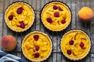 Summer custard tartlets with peaches and raspberry. Top view.