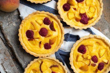 Summer custard tartlets with peaches and raspberry. Top view.